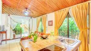A kitchen with a tiled countertop, a sink, and a window with curtains. - San Rafael Ecolodge (La Tigra)