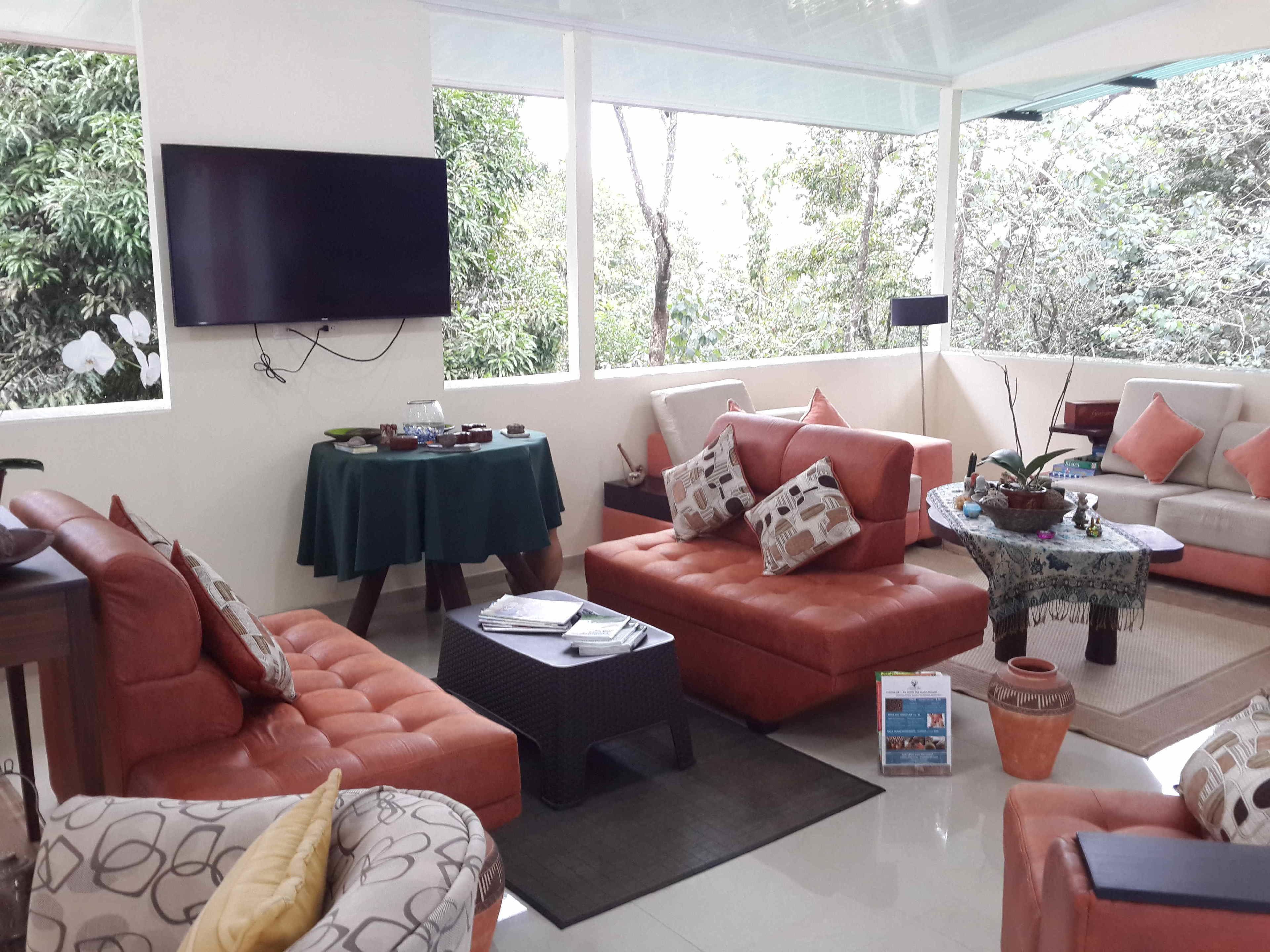 A modern living room with a sofa, armchairs, a coffee table, and a television mounted on the wall.