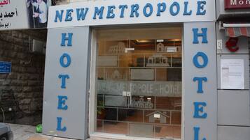 Un hotel llamado "New Metropole Hotel", con un letrero claro y una entrada visible.