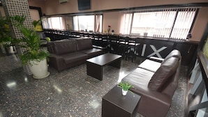 A lobby with a brown leather sofa, a matching armchair, a coffee table, and a potted plant. - New Metropole Hotel (Jerusalem)