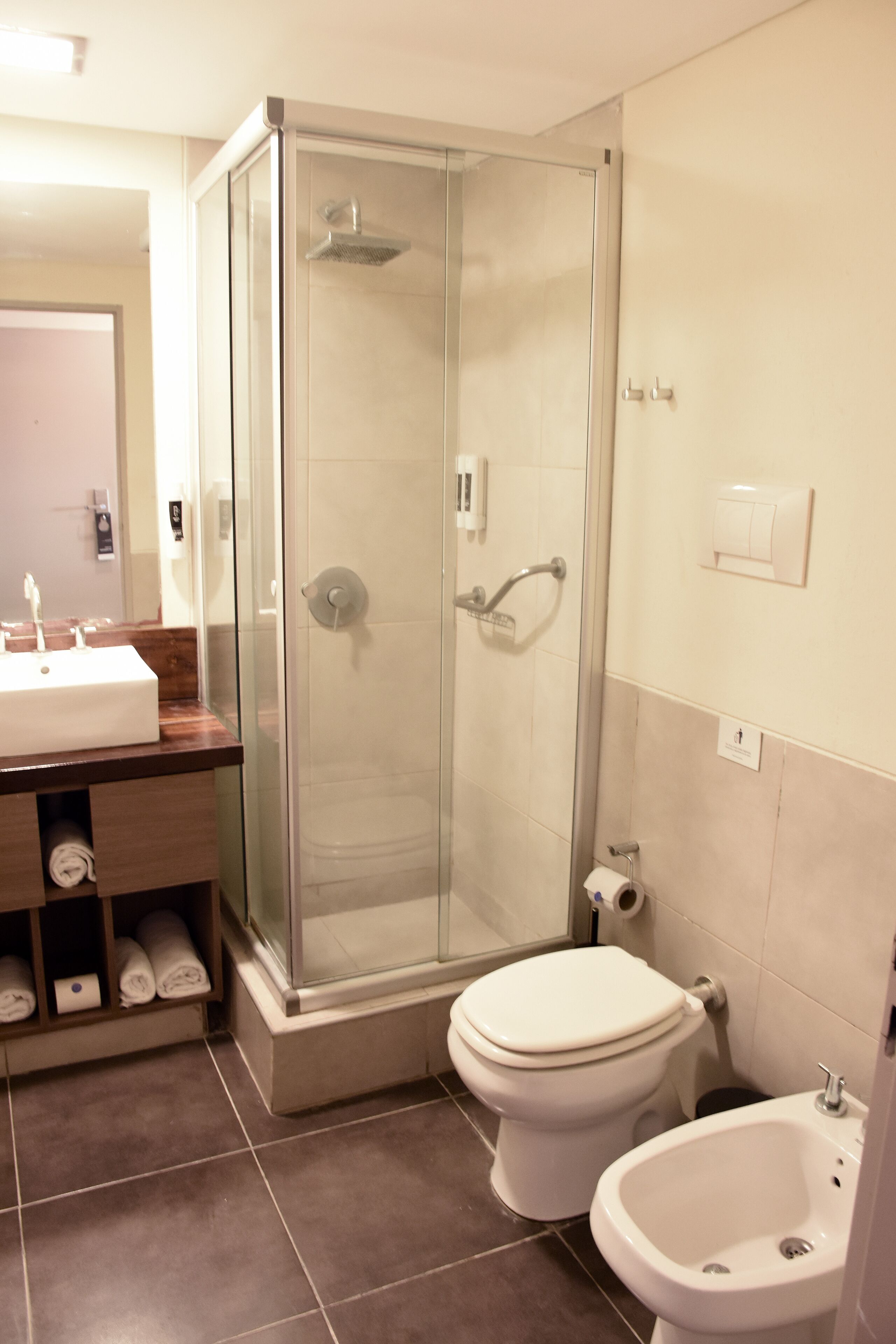 A bathroom with a glass-enclosed shower, a toilet, a bidet, and a sink with a mirror.