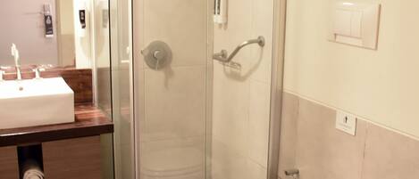 A bathroom with a glass-enclosed shower, a toilet, a bidet, and a sink with a mirror.