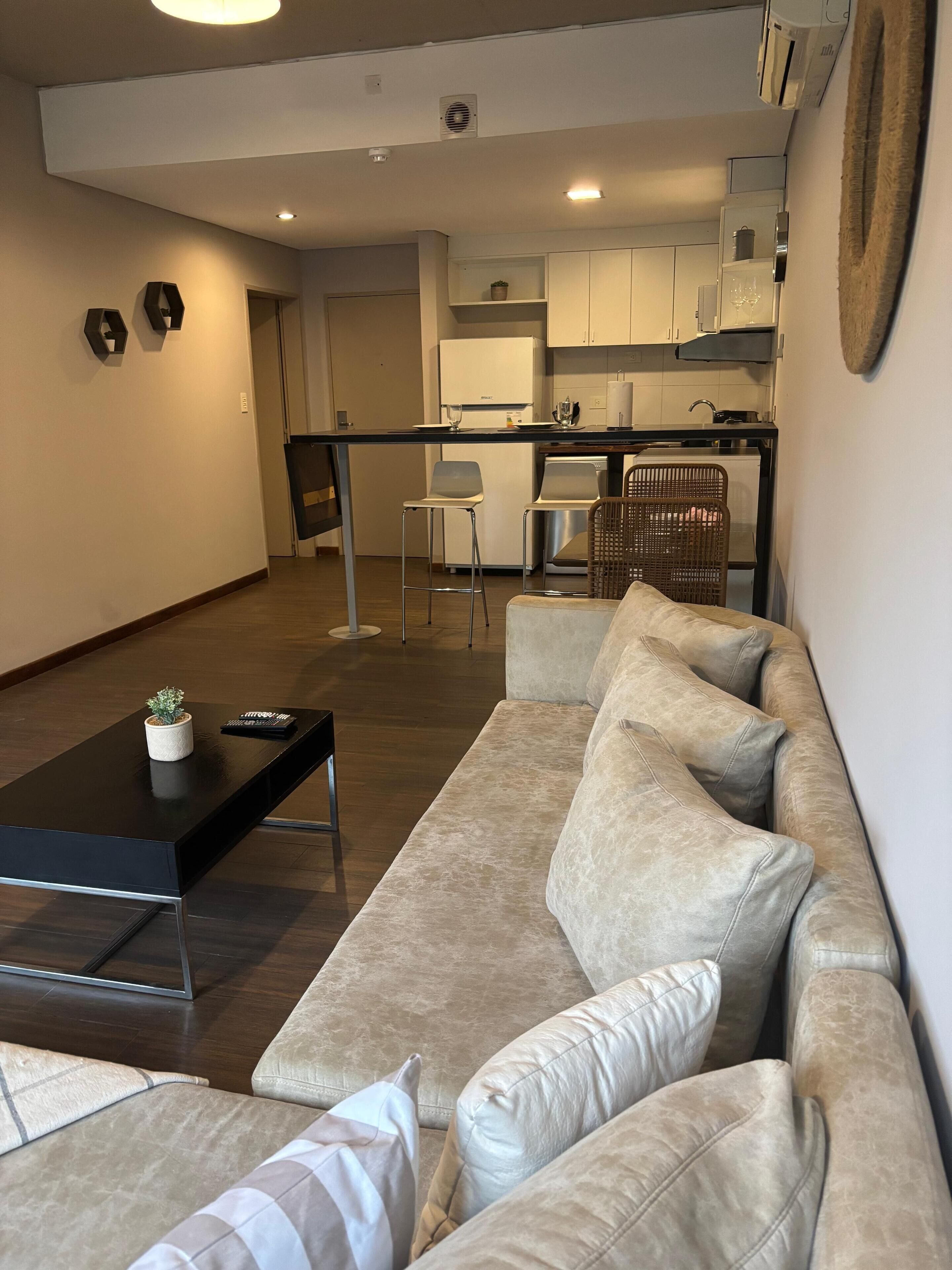 A modern living room with a beige sofa, a black coffee table, and a small potted plant.