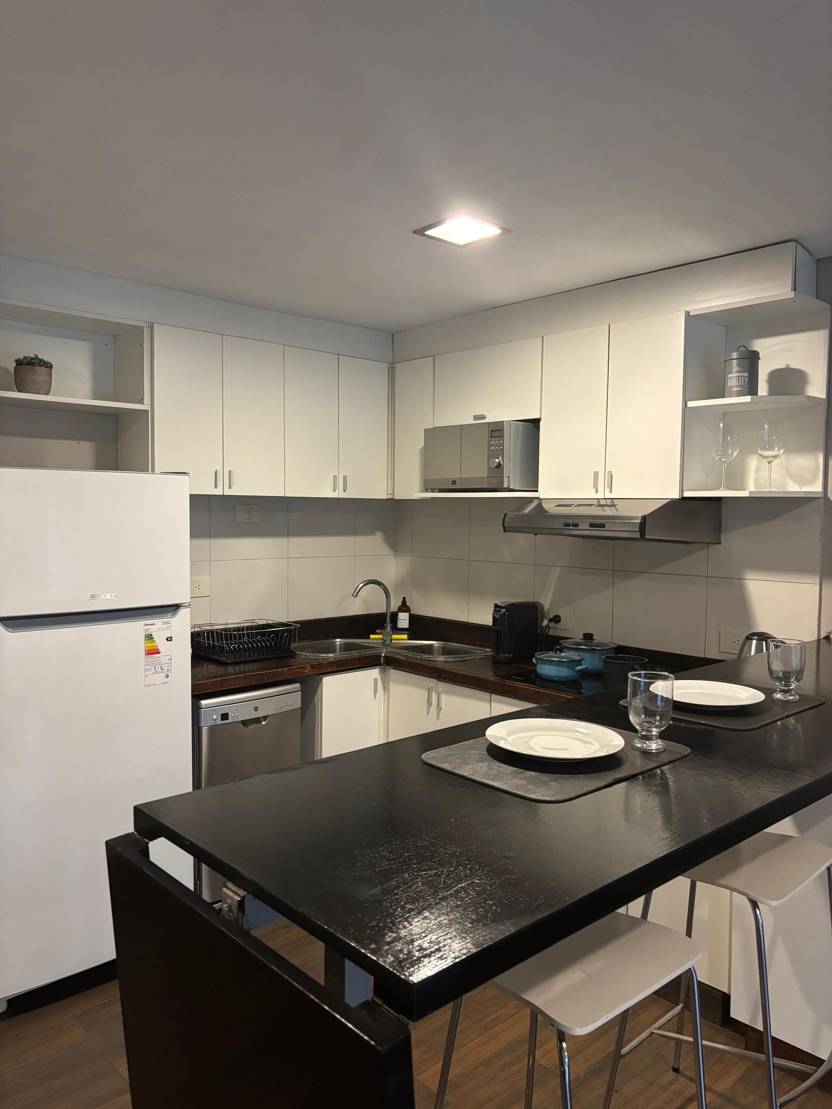 A modern kitchen with white cabinets, a black countertop, a built-in microwave, and a stove.
