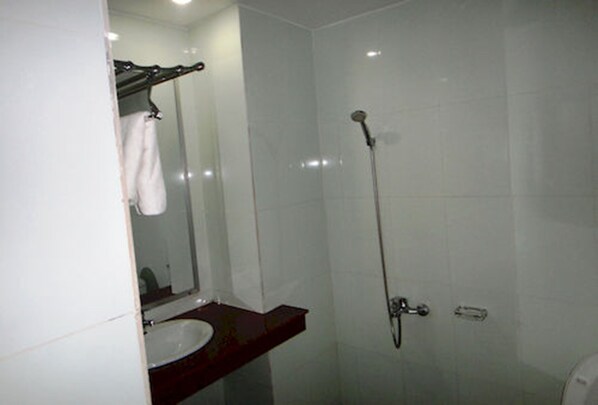 A bathroom with a white sink, a mirror, a towel rack, and a shower.