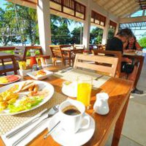 Guests can enjoy casual dining in this inviting space with tables and chairs, featuring refreshments and a warm atmosphere.