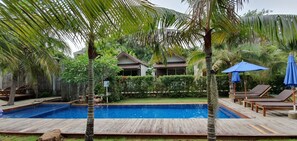 Relax by the serene pool surrounded by lush greenery and comfortable lounge chairs.