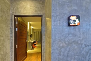 A hallway with a wooden door leading to a room with a desk and a chair. - The Oasis Resort (Krabi)