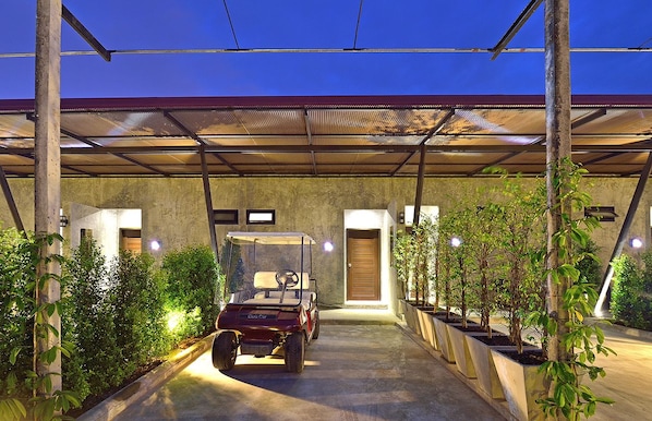 A covered parking area with a golf cart, concrete walls, and potted plants.