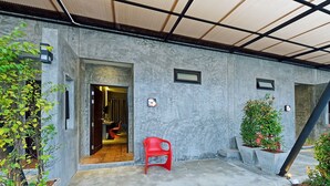 A modern building exterior with a concrete facade, a red plastic chair, and potted plants. - The Oasis Resort (Krabi)