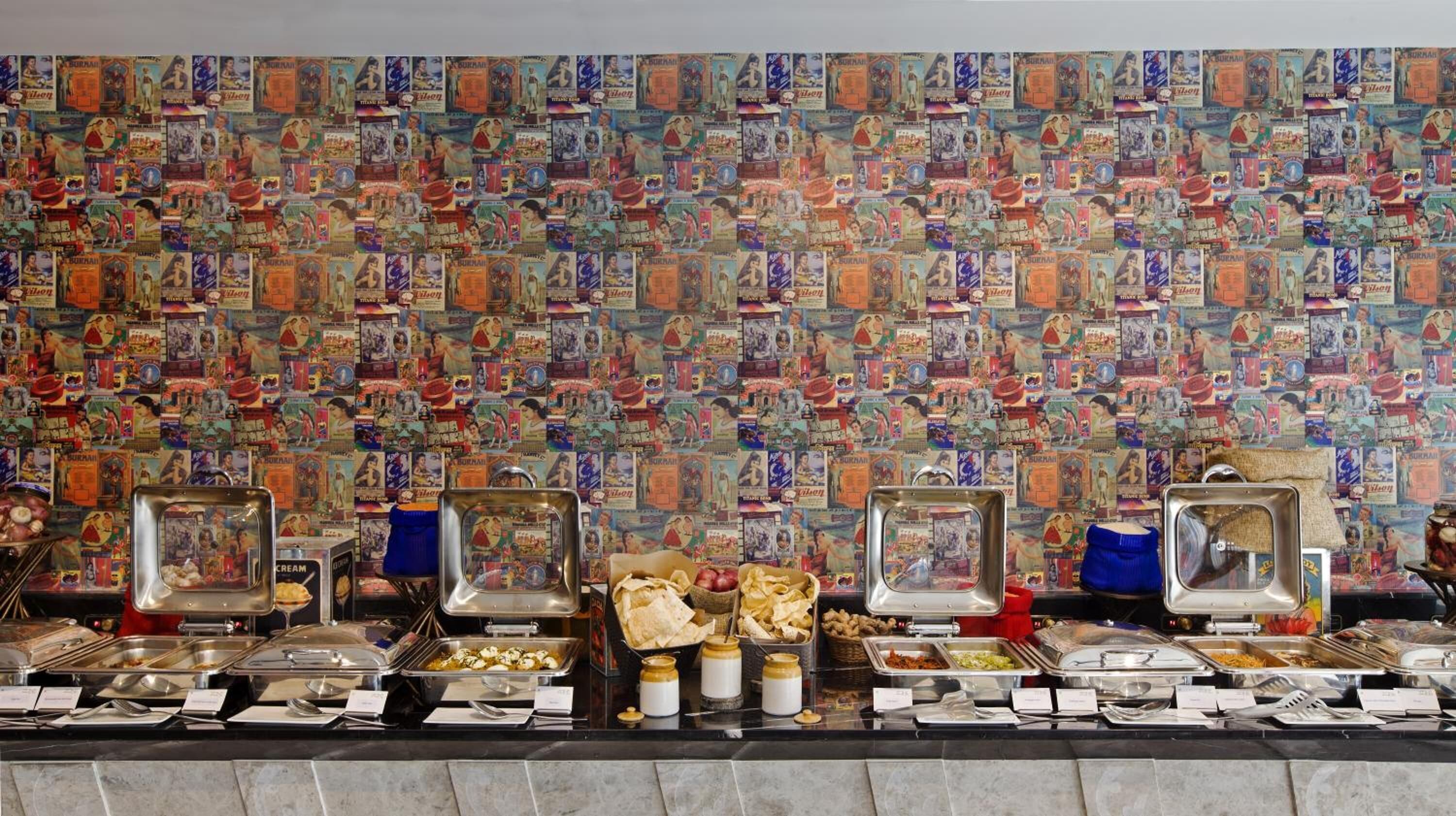 A buffet with various food items and a wall decorated with vintage magazines.