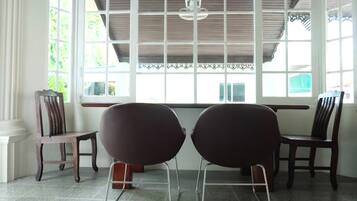 Una habitación con dos sillas modernas, una silla de madera y una ventana con vista a follaje.