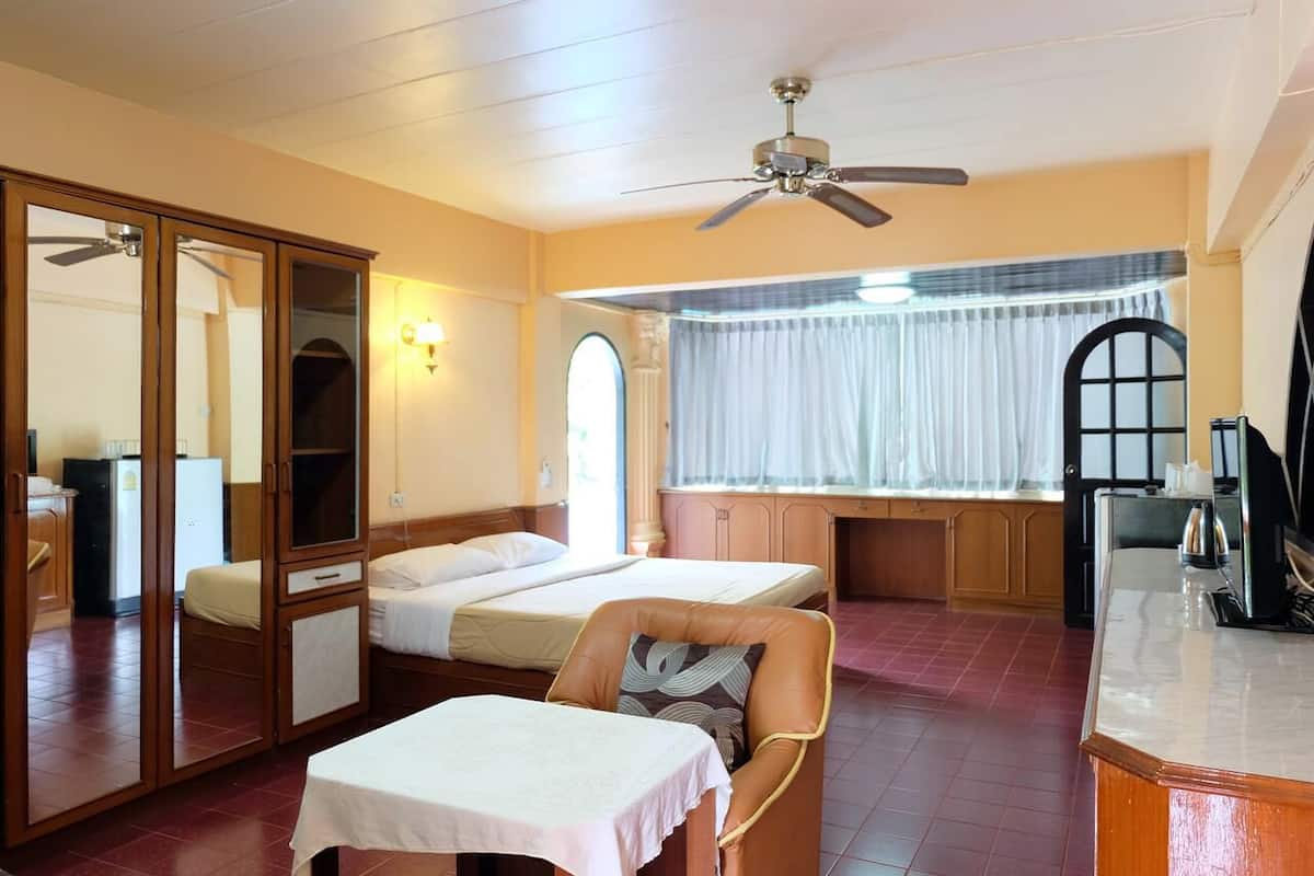 Habitación de hotel con dos camas, una mesa de comedor, una silla, un ventilador de techo y una ventana con cortinas.
