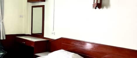Une chambre d’hôtel avec un lit, une table de chevet, un miroir et une lampe suspendue.