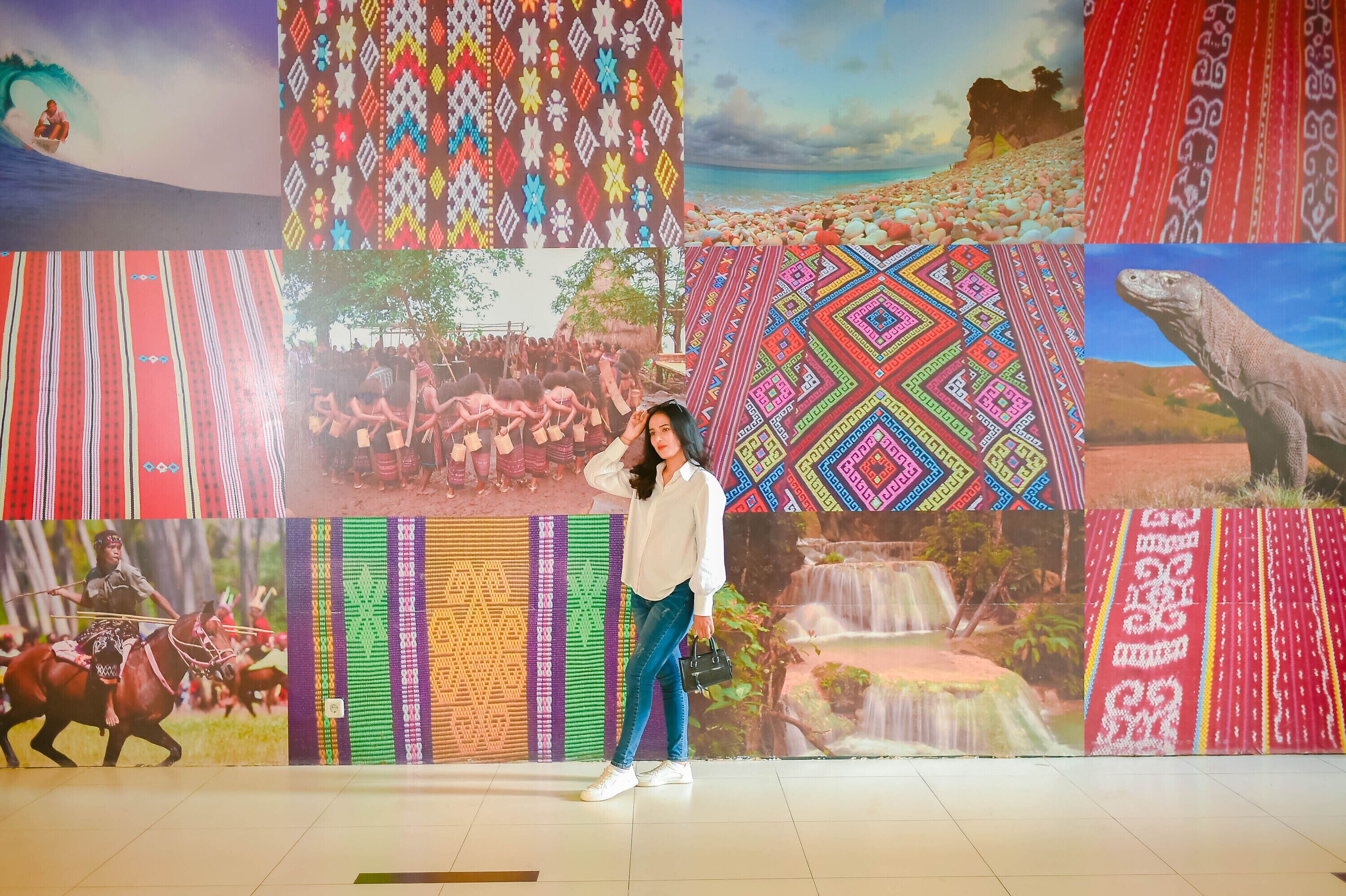 A person standing in front of a wall with various cultural patterns.