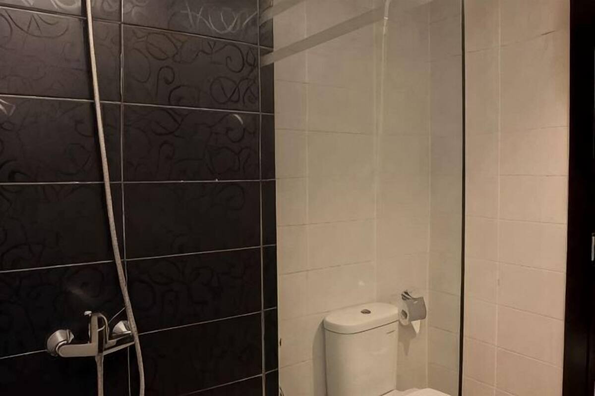 A bathroom with a shower, a toilet, and a hand dryer.