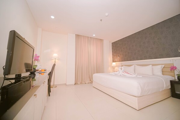 A hotel room with a bed, a TV, a desk, and a lamp. - Sahid T-More Kupang (Kupang)