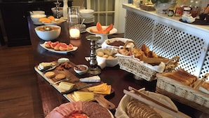 Une table de buffet proposant une variété d’aliments, notamment des viandes, des fromages et des pains.