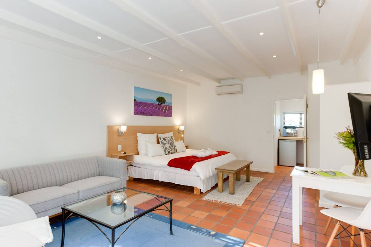Ein modernes Hotelzimmer mit Bett, einer Couch, einem kleinen Tisch und einem Fernseher.
