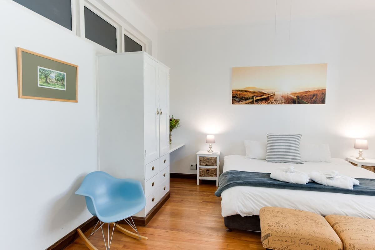 Ein Schlafzimmer mit einem Bett, einem Nachttisch, einem Sessel, einem Kleiderschrank und einem Bild an der Wand.
