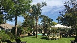 Un espace extérieur bien aménagé, doté d’une piscine, de chaises longues et de parasols.