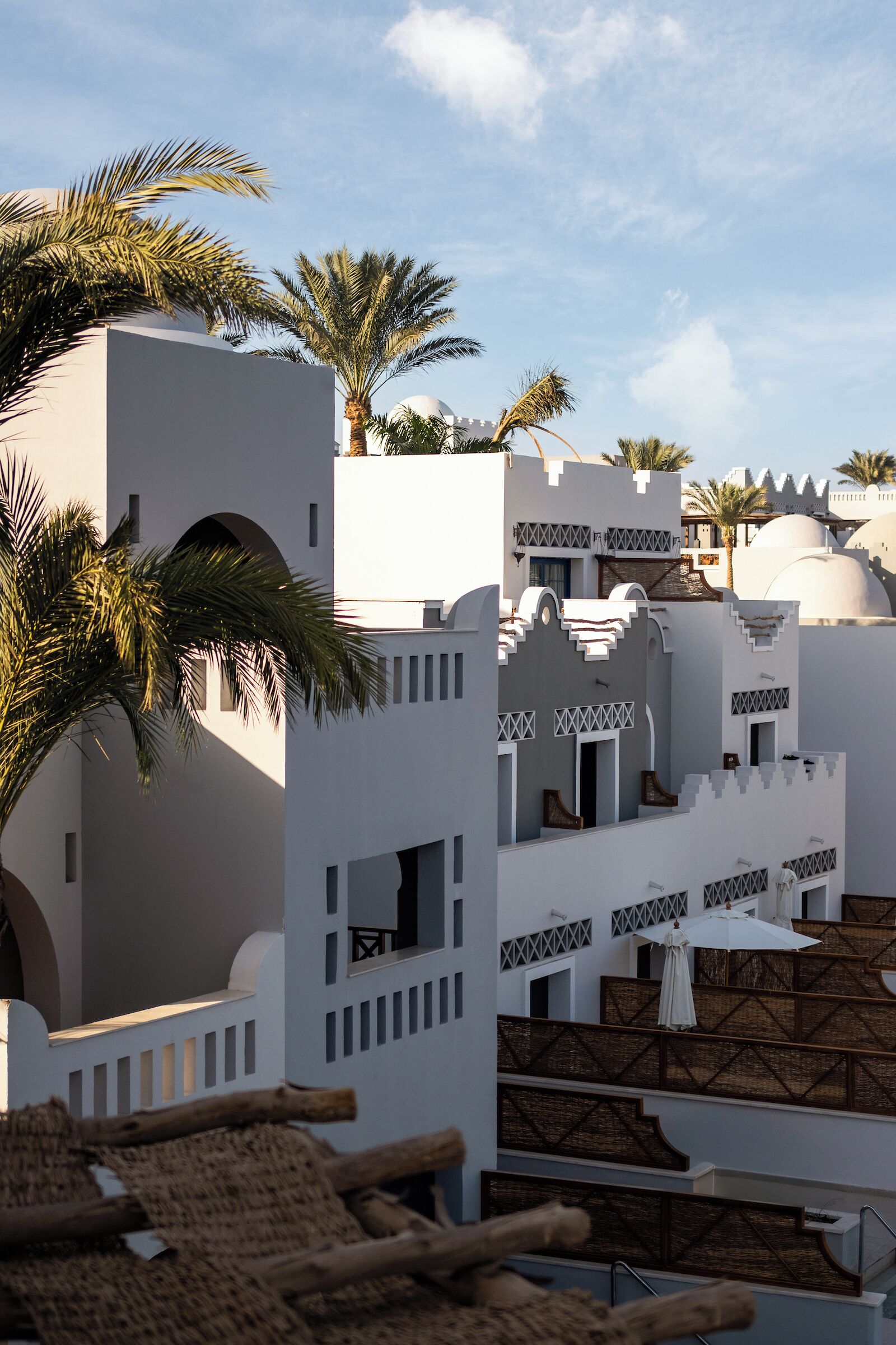 A resort with white buildings, palm trees, and a clear sky.
