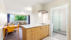 Une cuisine compacte avec un coin repas, une douche en verre et une vue sur la verdure environnante.