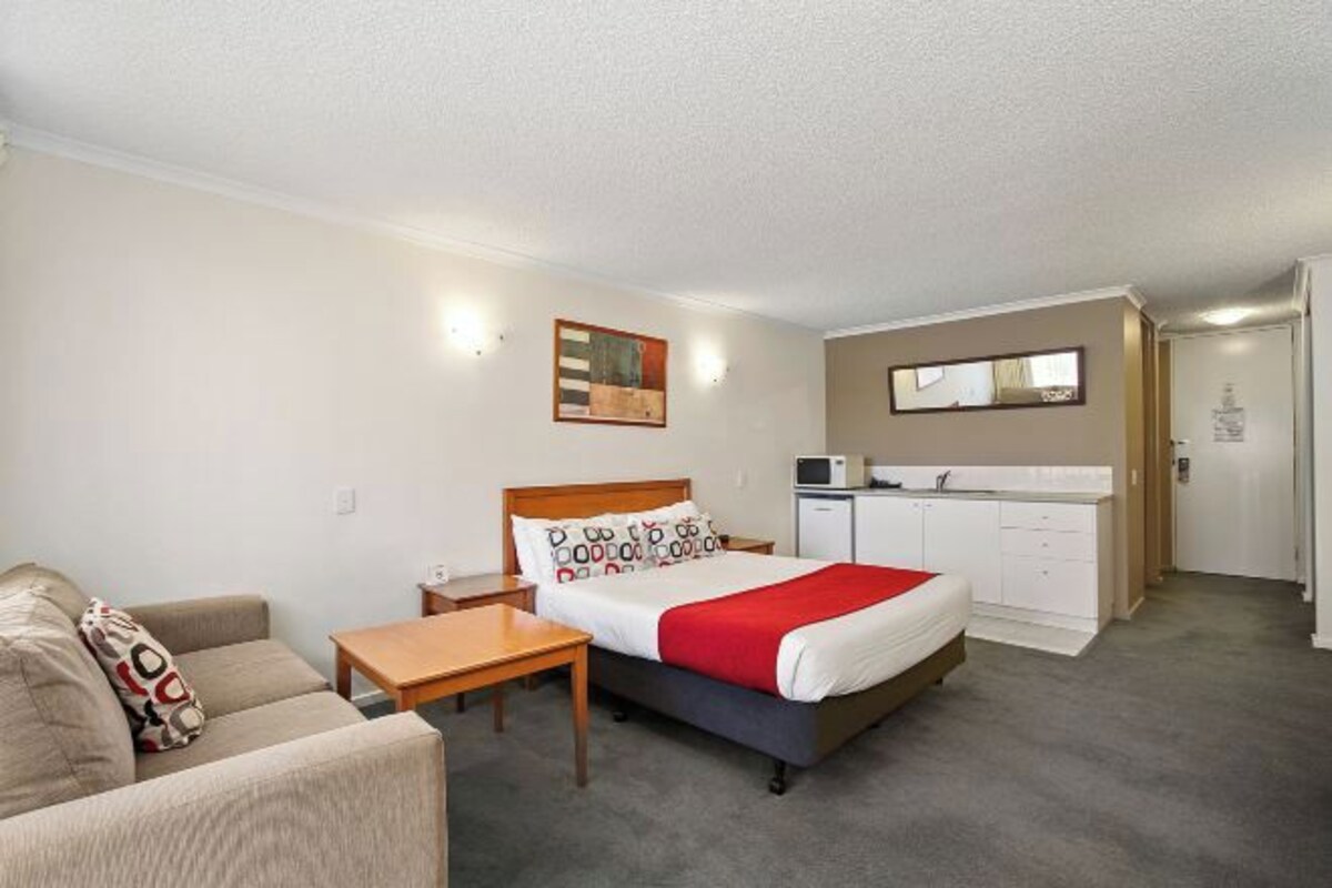 Ein Hotelzimmer mit Bett, einer Sitzecke, Schreibtisch, kleinem Tisch, Mikrowelle, Minikühlschrank und Badezimmer.