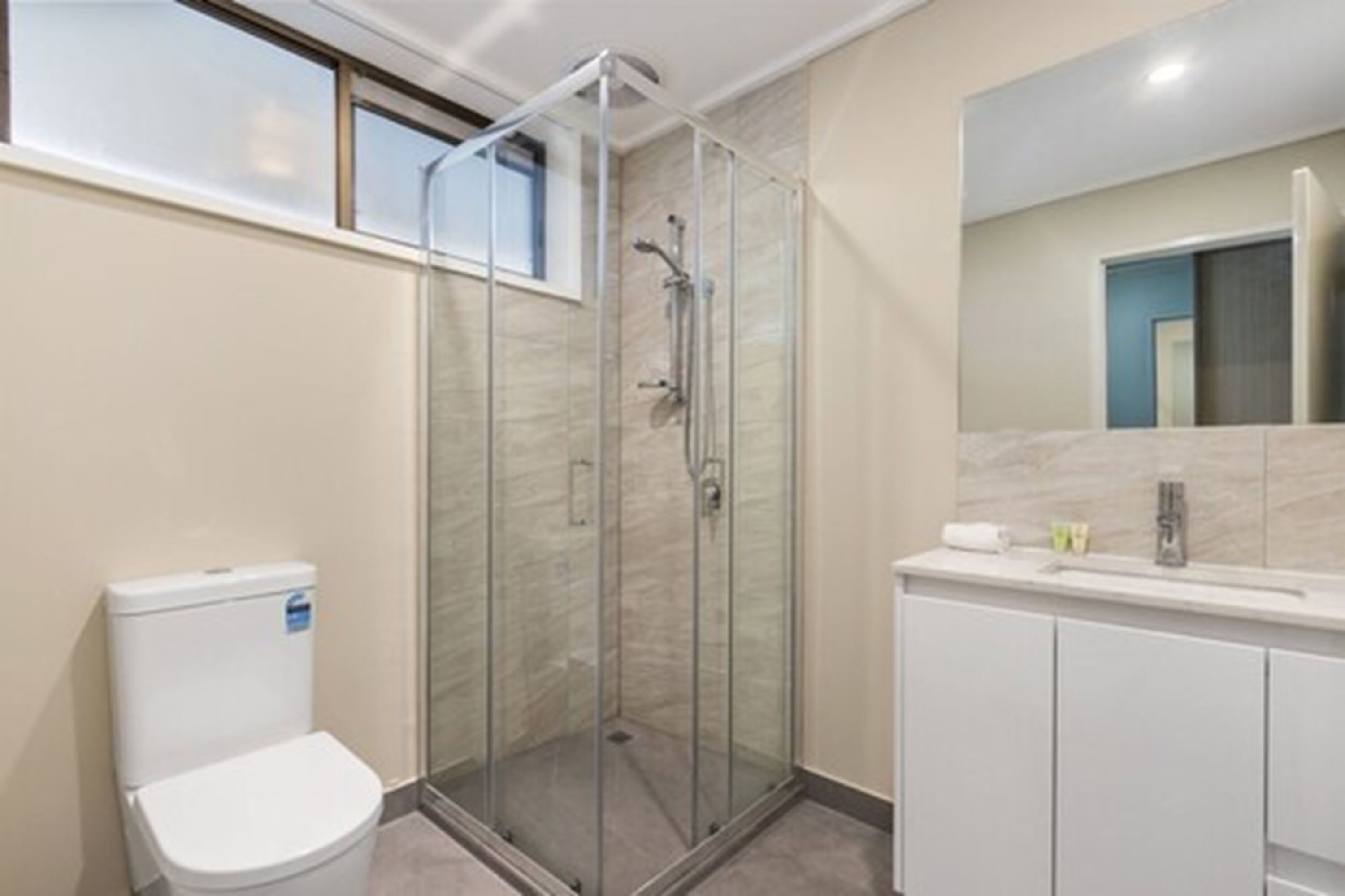 Une salle de bain moderne avec une douche à parois de verre, des toilettes et un meuble-lavabo avec un miroir.
