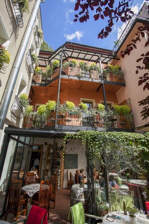 A multi-level outdoor cafe with tables and chairs, surrounded by balconies with plants. - Aparthotel Vicini (Kraków)