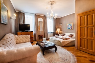 A spacious bedroom with a large bed, a sitting area with a sofa and coffee table, a television, and a chandelier.