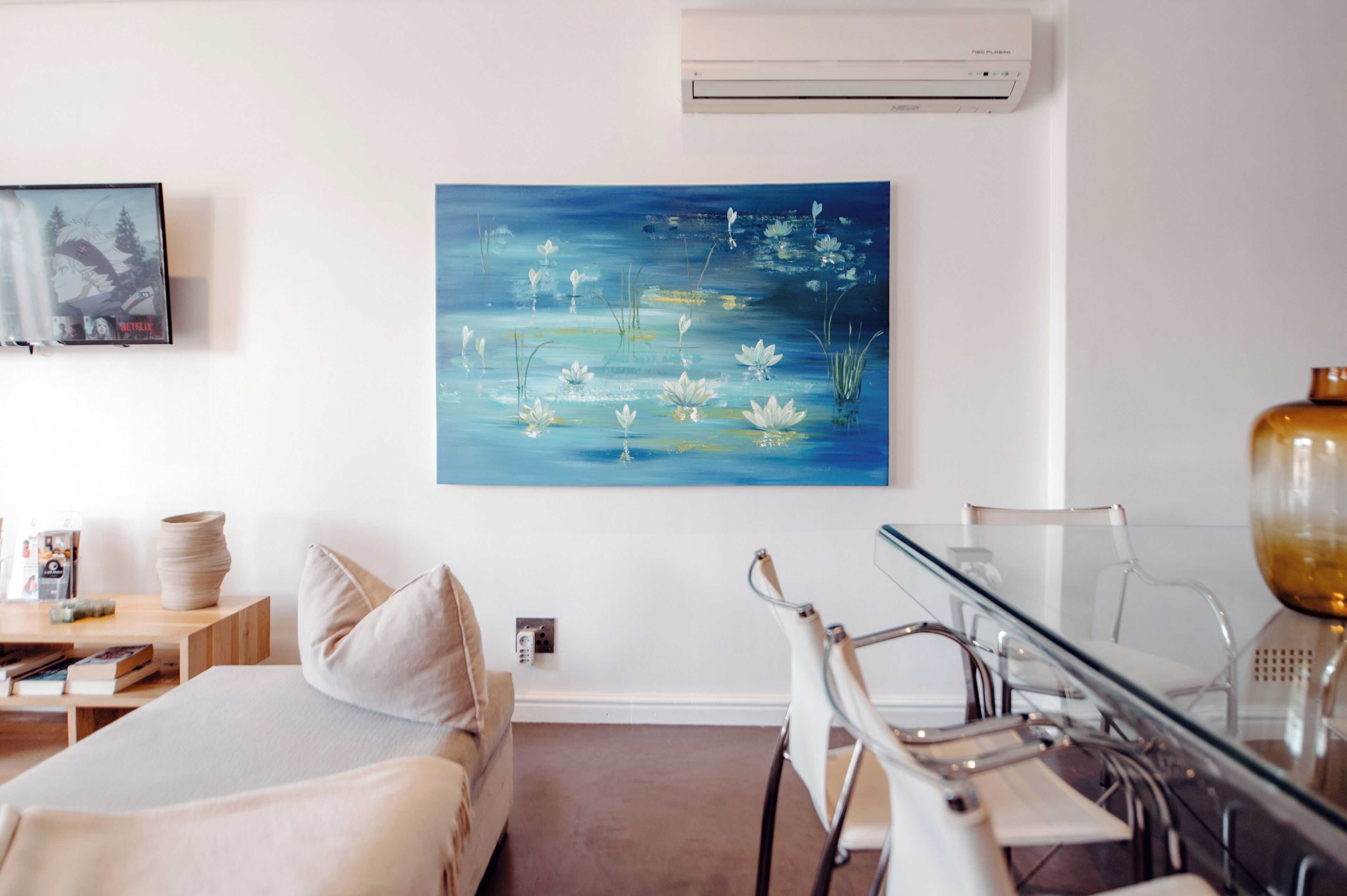 Une chambre d’hôtel avec un lit, un bureau, une chaise et un tableau représentant un étang parsemé de fleurs.
