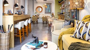 A modern interior with a dining area, a sofa with patterned cushions, and a wooden cabinet with glass doors. - Cape Finest Guesthouse (Cape Town)