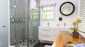 A modern bathroom with a glass-enclosed shower, a wooden vanity with a mirror, and a checkered floor.