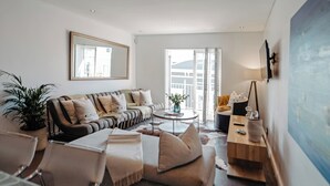 A modern living room with a sectional sofa, a coffee table, and a painting on the wall. - Cape Finest Guesthouse (Cape Town)