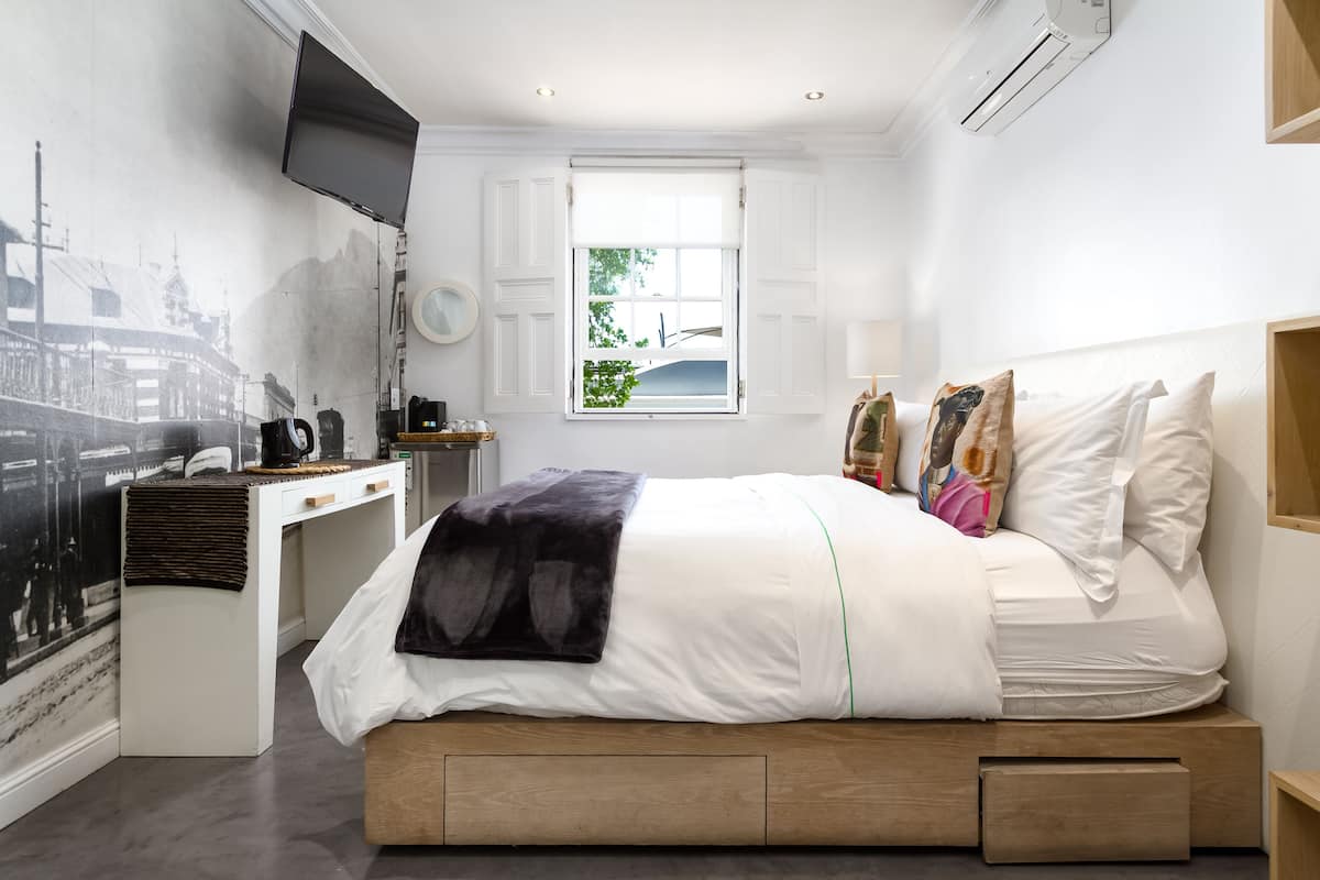 Quarto moderno com cama, mesa de cabeceira e escrivaninha com cadeira.