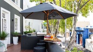 An outdoor seating area with a table, chairs, and an umbrella. - Cape Finest Guesthouse (Cape Town)