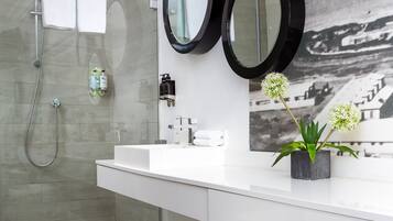 A modern bathroom with a glass-enclosed shower, white vanity, and three round mirrors.