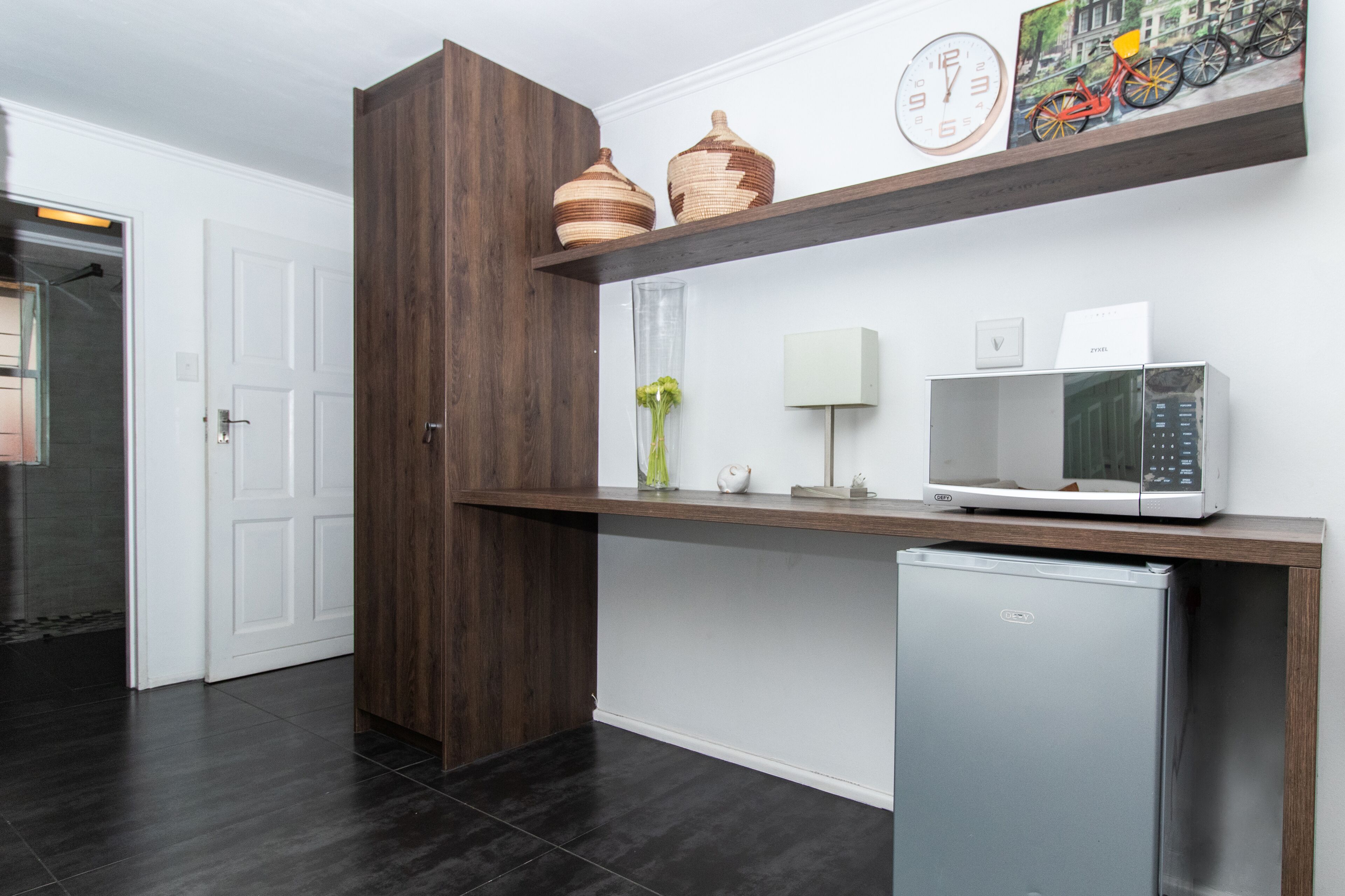 A kitchen with dark wood cabinetry, a white refrigerator, a microwave, and decorative items on a shelf.