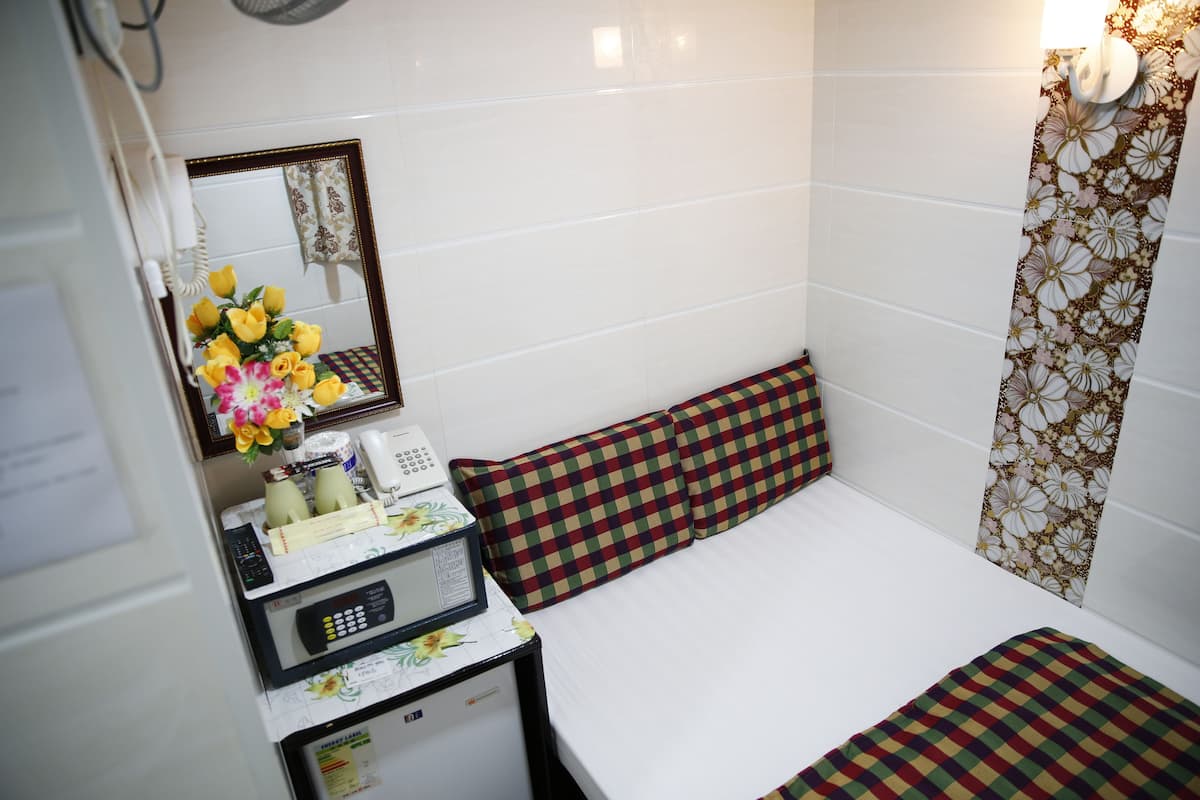 A hotel room with a bed, a small desk with a telephone, a microwave, and a mirror.