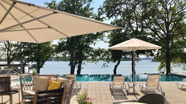 A poolside area with lounge chairs, umbrellas, and a view of the sea. - Gränsö Slott Hotel & Spa (Vastervik)