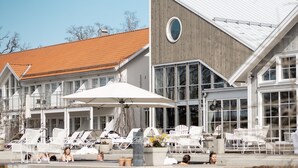 A hotel with a pool area featuring lounge chairs and umbrellas, large windows, and a distinctive wooden and metal facade. - Gränsö Slott Hotel & Spa (Vastervik)