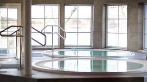 A large indoor swimming pool with clear glass walls, a metal handrail, and a view of trees outside. - Gränsö Slott Hotel & Spa (Vastervik)
