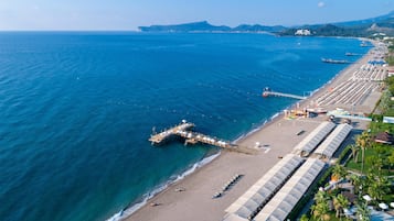 Privat strand, solstolar, parasoller och volleyboll