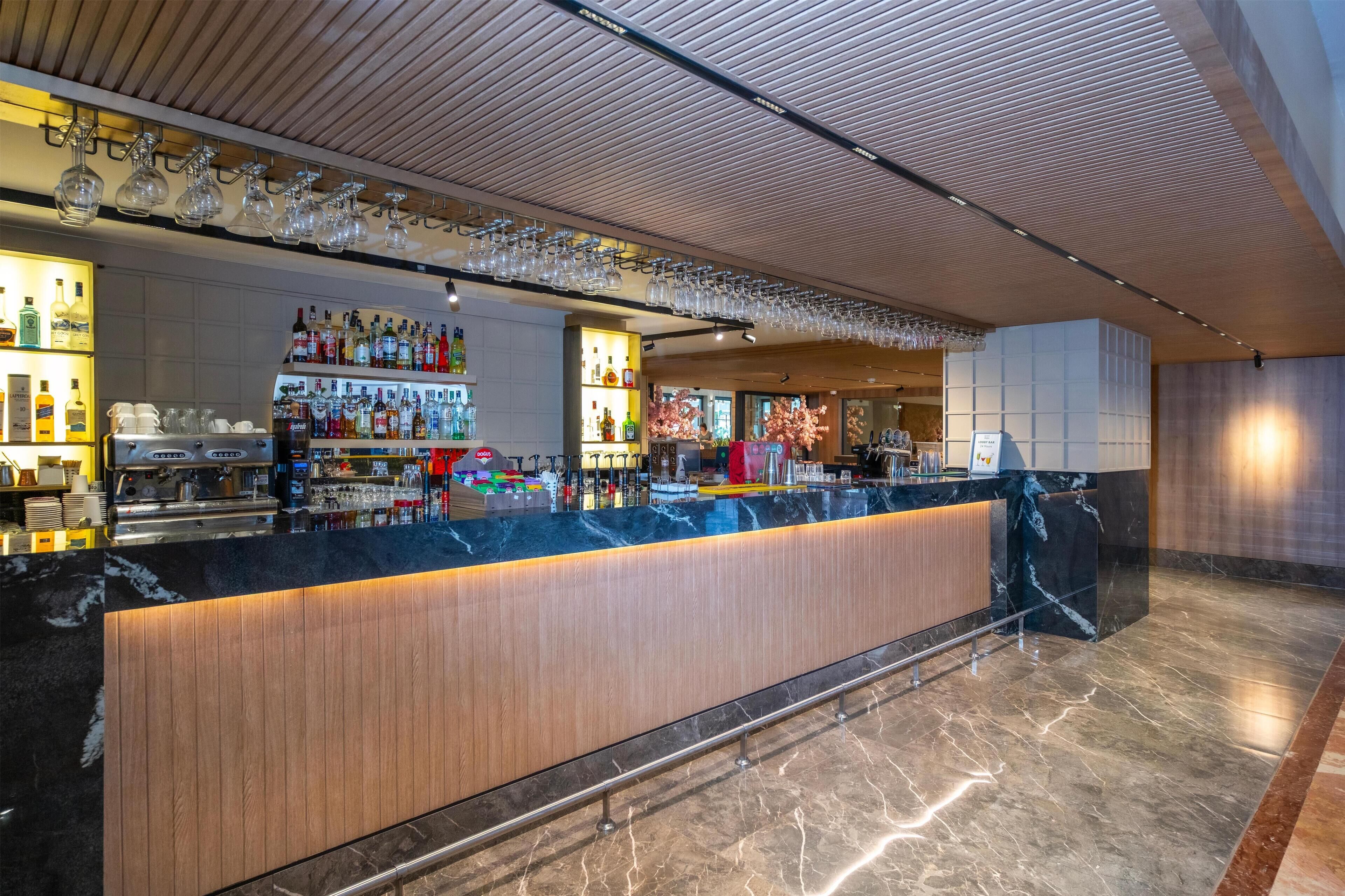 A modern bar area with a marble countertop, wooden paneling, and a variety of liquor bottles.