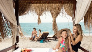 A beach setting with a thatched roof structure, a table with a fruit platter, and a view of the sea and beach chairs. - Seven Seas Hotel Life - Ultra All Inclusive (Kemer)
