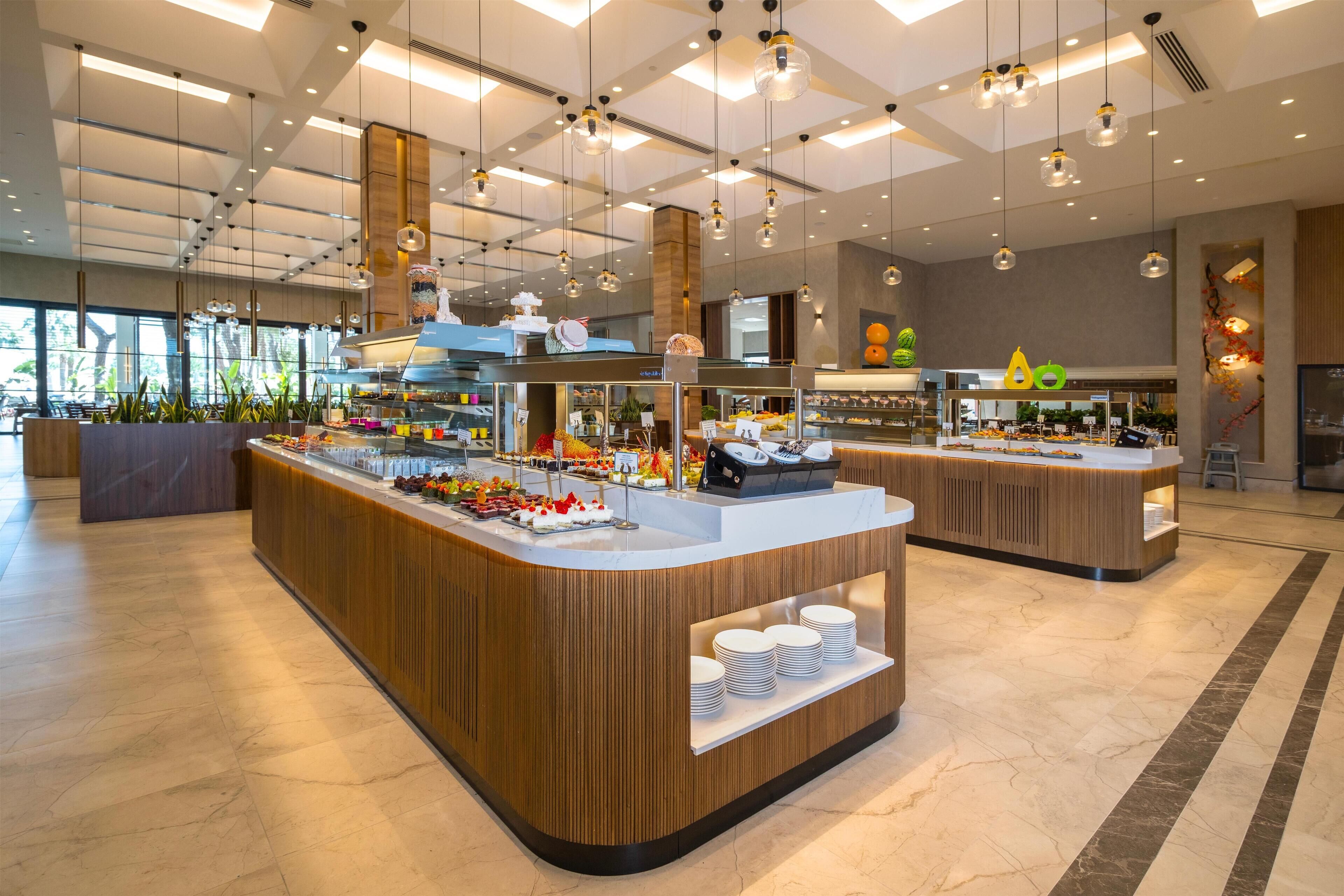 A modern buffet area with wooden counters, a variety of food items, and hanging pendant lights.