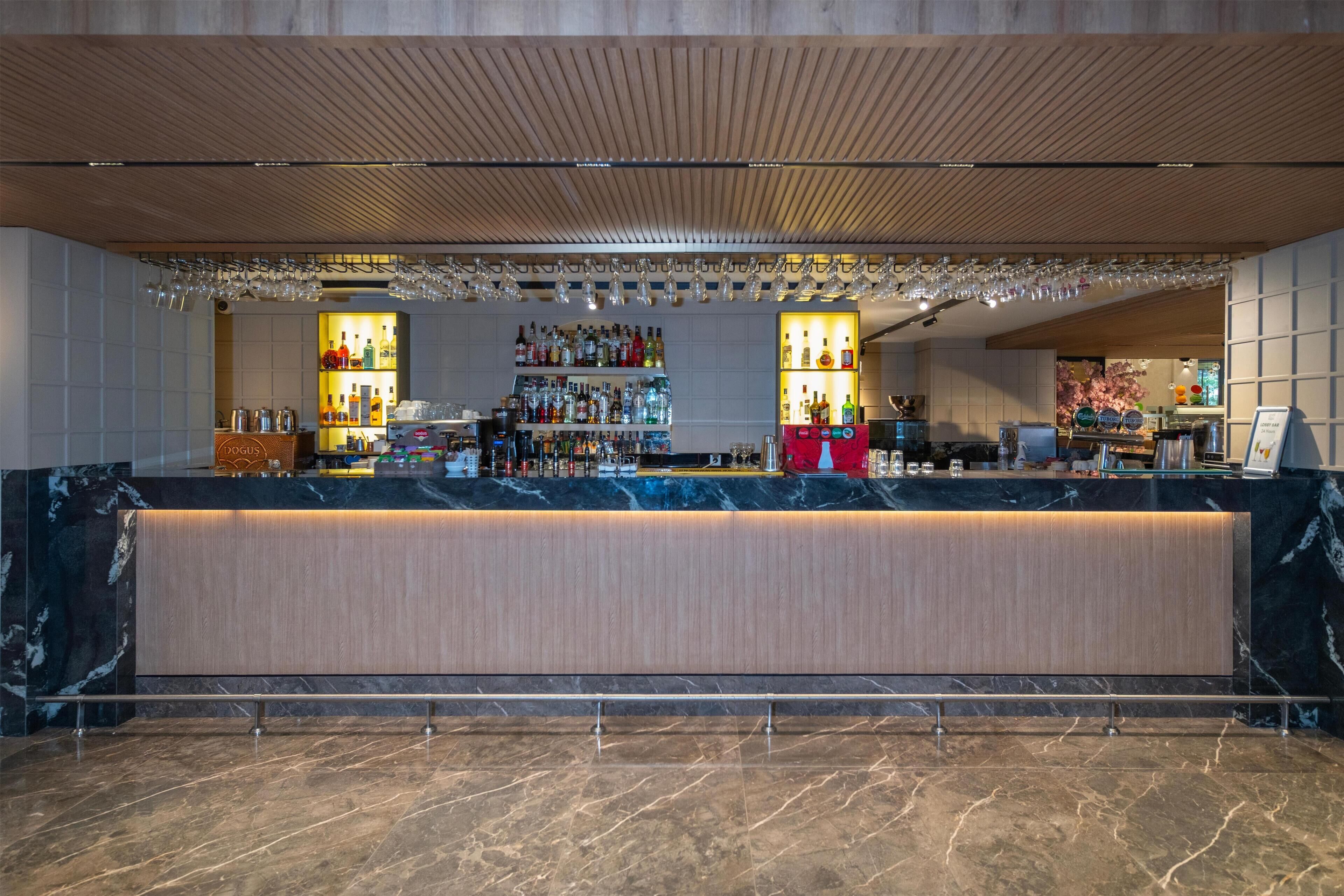 A bar area with a marble countertop, shelves of liquor bottles, and hanging glasses.