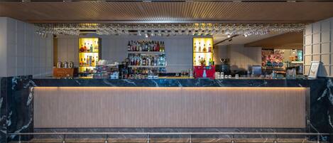 A bar area with a marble countertop, shelves of liquor bottles, and hanging glasses.