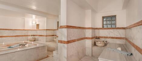 Un baño con tocador de mármol, bañera y ventana.